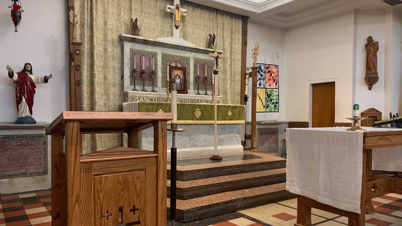 The altar at Our Saviour, with candles, a crucifix, and Sanctus carved above the altar table
